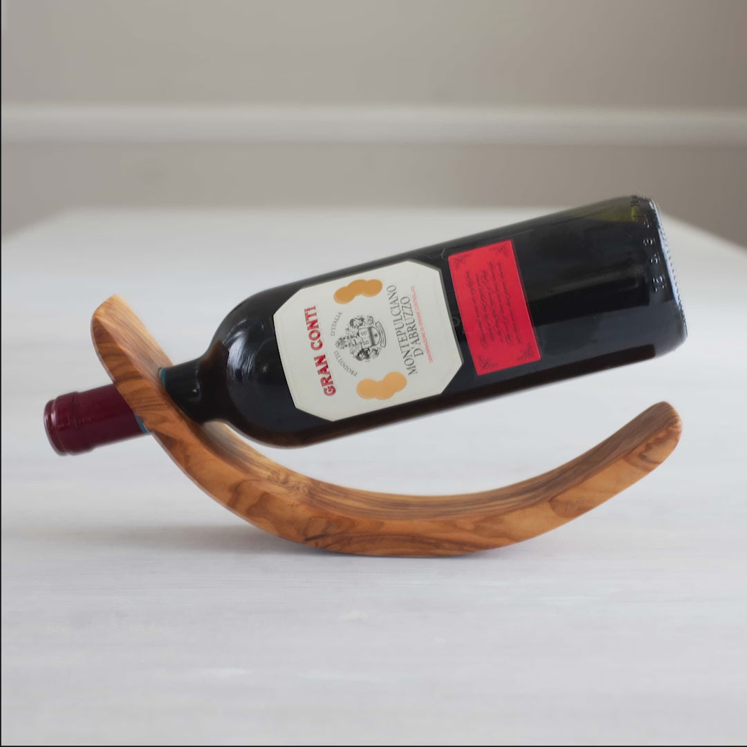 video showing how to stick a bottle in the wine bottle display made from olive wood